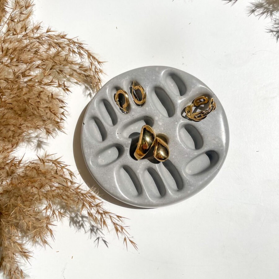 Coupelle à bijoux en béton artisanale avec bagues et boucles d'oreilles, décoration minimaliste fabriquée à la main.