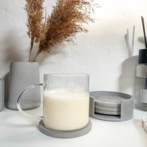 Lot de 4 dessous de verre ronds en béton avec support de rangement dans une décoration minimaliste.