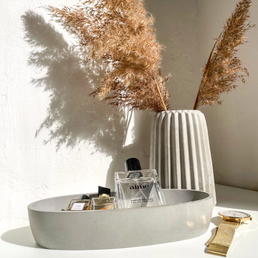 Petite coupelle en béton utilisée comme porte-bijoux ou vide-poche dans une décoration contemporaine.