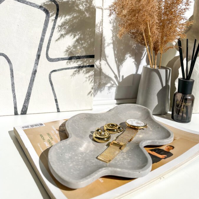 Plateau ondulé en béton utilisé comme vide-poche ou rangement à bijoux design dans une décoration contemporaine.