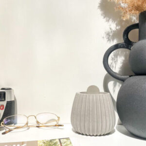 Pot avec couvercle en béton strié dans une décoration minimaliste, fabrication artisanale.