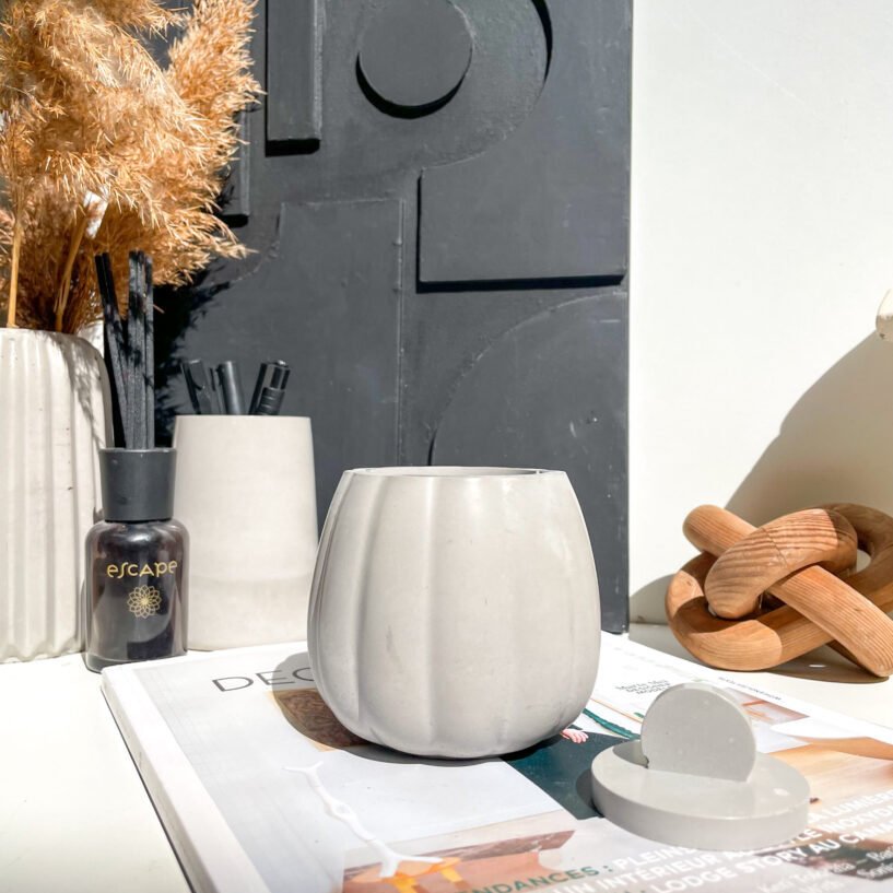 Pot organique avec couvercle en béton pour rangement d'accessoires de bureau.