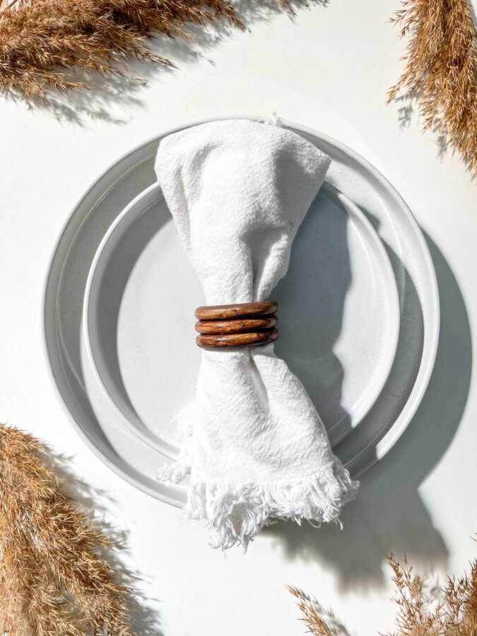 Rond de serviette en bois utilisé avec une serviette en tissu pour une table raffinée.