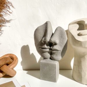 Sculpture visages enlacés en béton dans une décoration intérieure minimaliste.