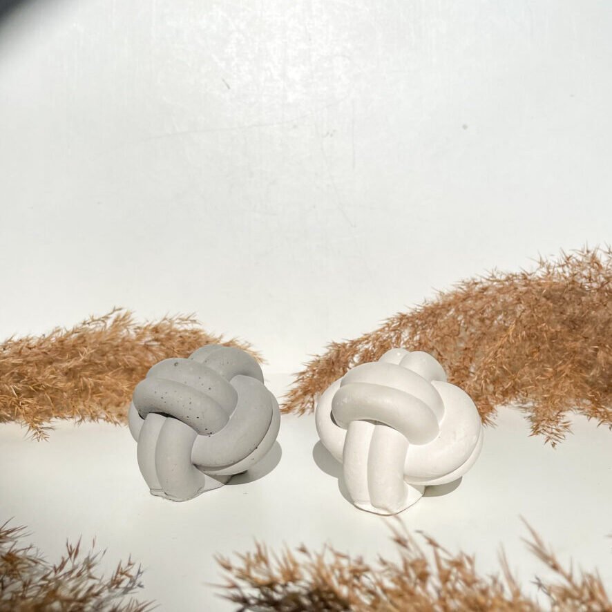 Petits nœuds marins en béton disponibles en trois coloris, gris et blanc sur la photo.